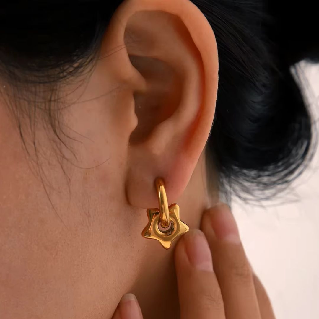 Puffy star earrings on person